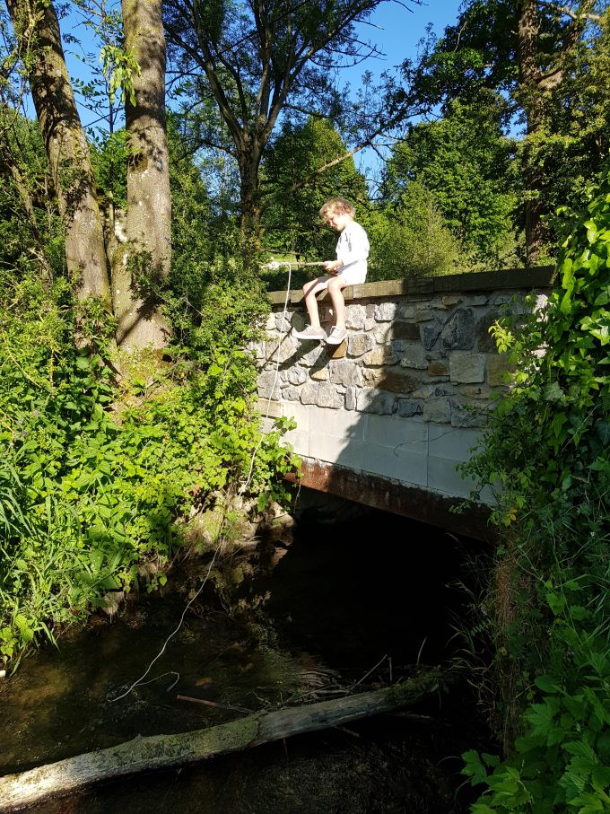 garçonnet pêchant du haut d'un petit pont de pierre